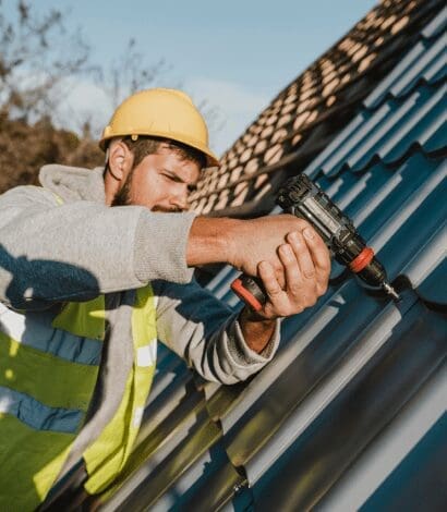 Worker installing roof using a drill.