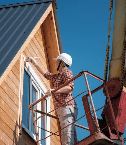 Painter on lift painting house siding.